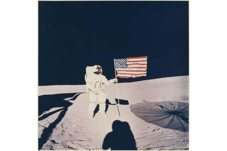 Shepard ao lado da bandeira americana, em Fra Mauro Bare. Sombra de Michell na frente, 1971 | Foto: NASA/Divulgação