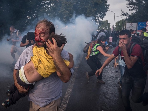 Um homem tenta proteger uma crianÃ§a apÃ³s ataque da polÃ­cia na fronteira em Horgos, na SÃ©rvia | Foto: Sergey Ponomarev/The New York Times/The Pulitzer Prize